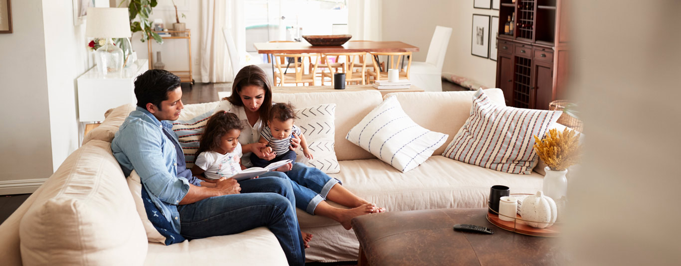 Family sitting on the sofa looking at a book together